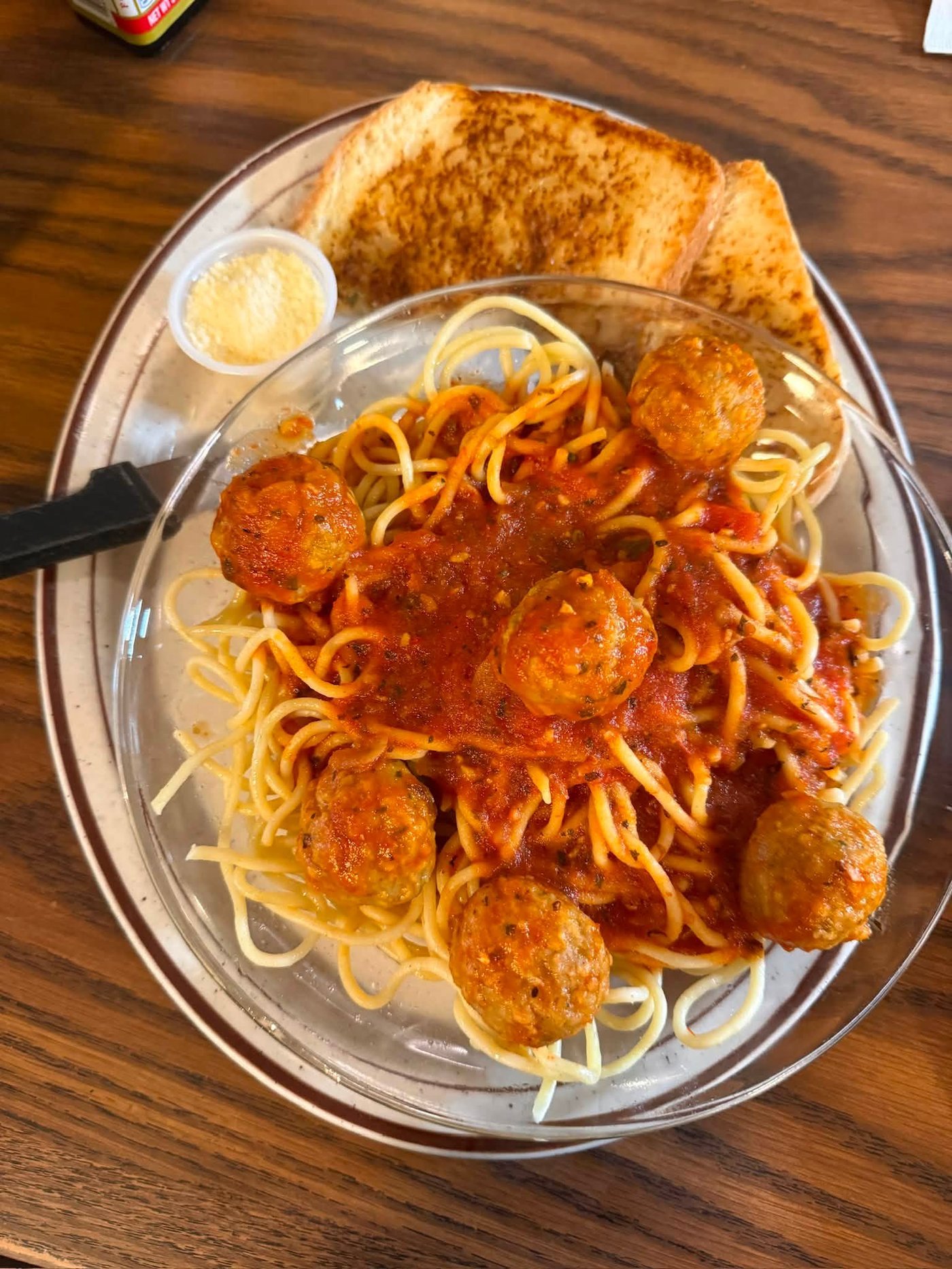 Spaghetti and meatballs in red sauce with garlic bread and parmesan